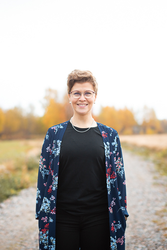 Laura katsoo kameraan, taustalla ruska.